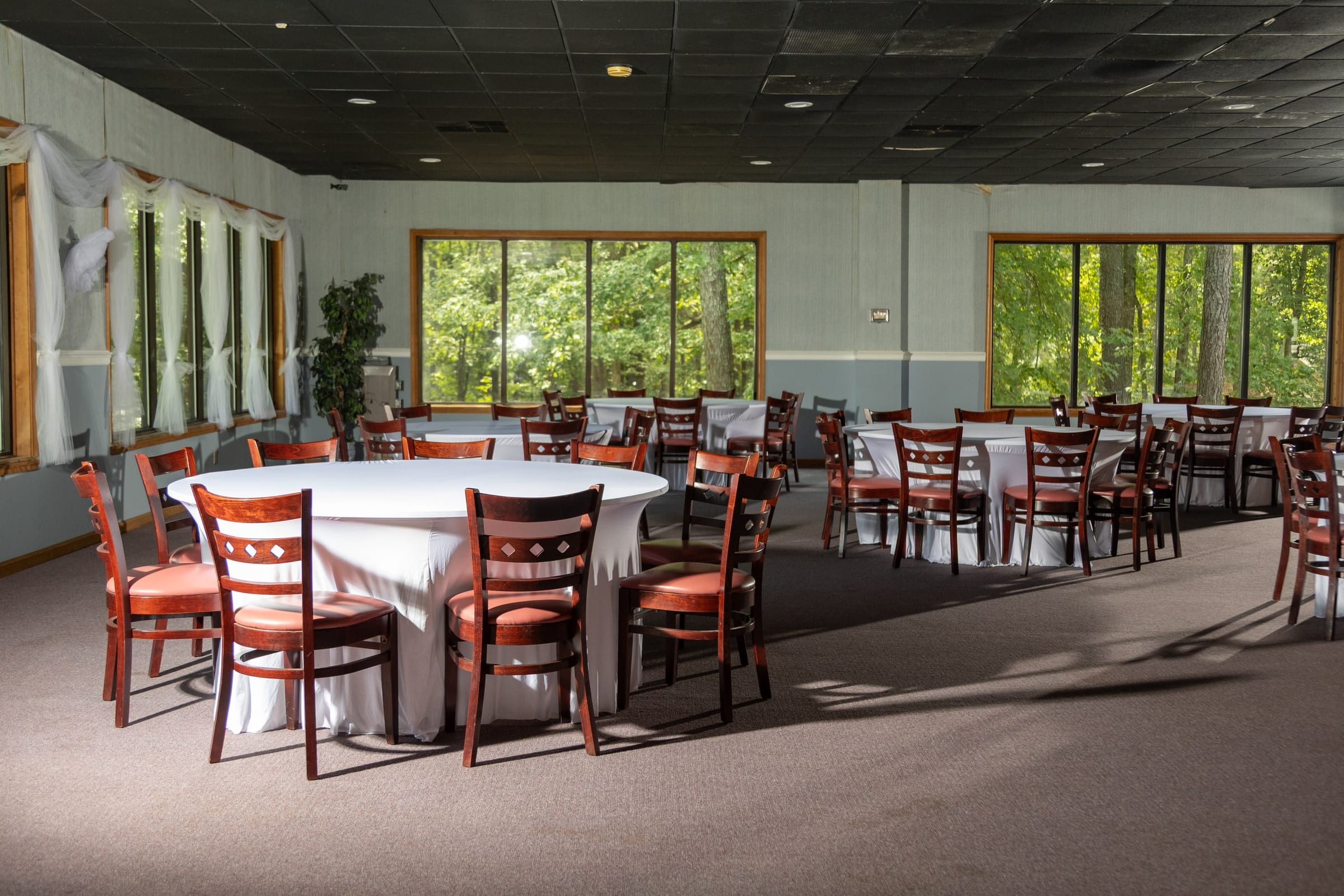 Banquet room set with clothed round tables and red chairs