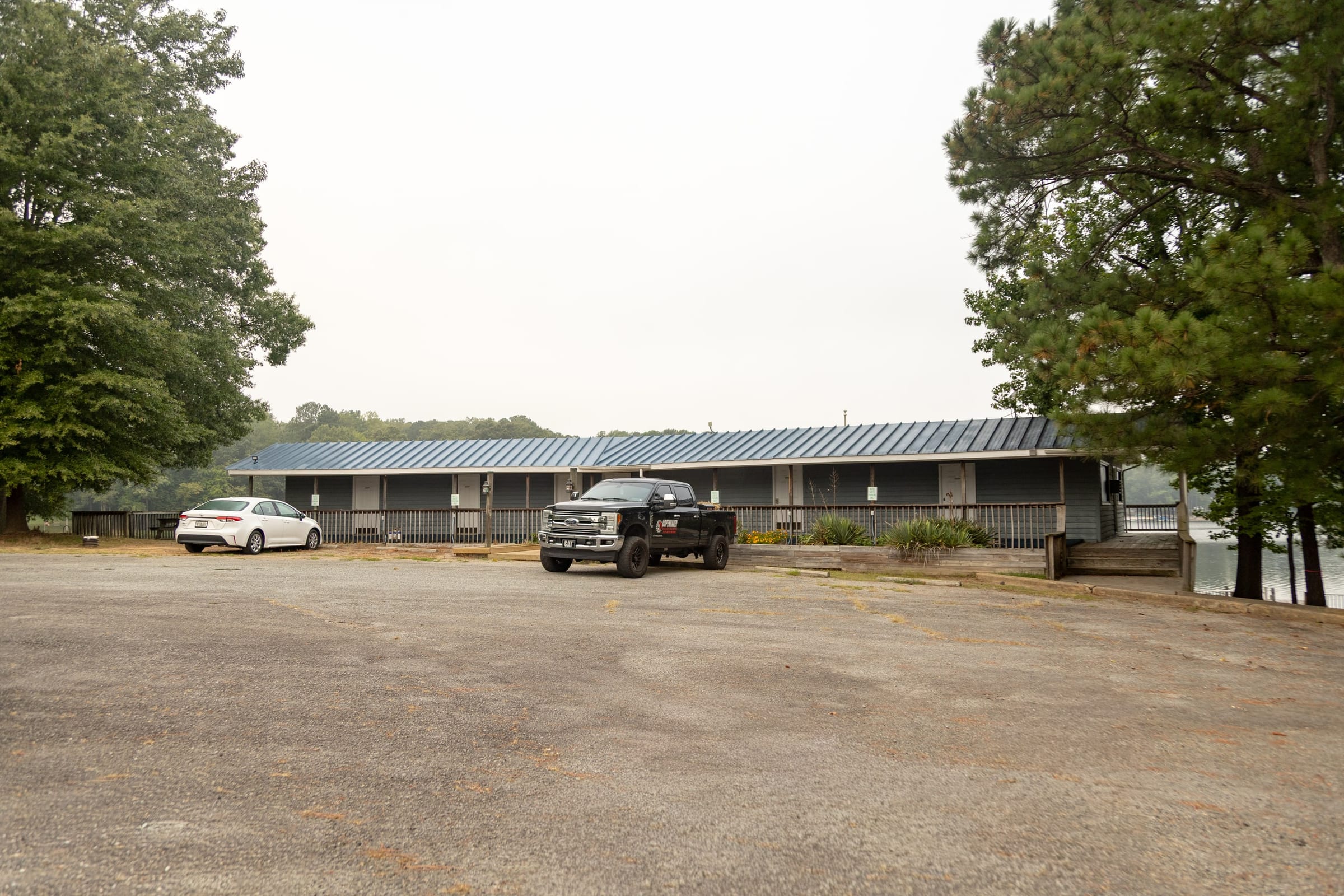 Long blue-roofed resort building across its parking lot, a pickup and sedan parked outside