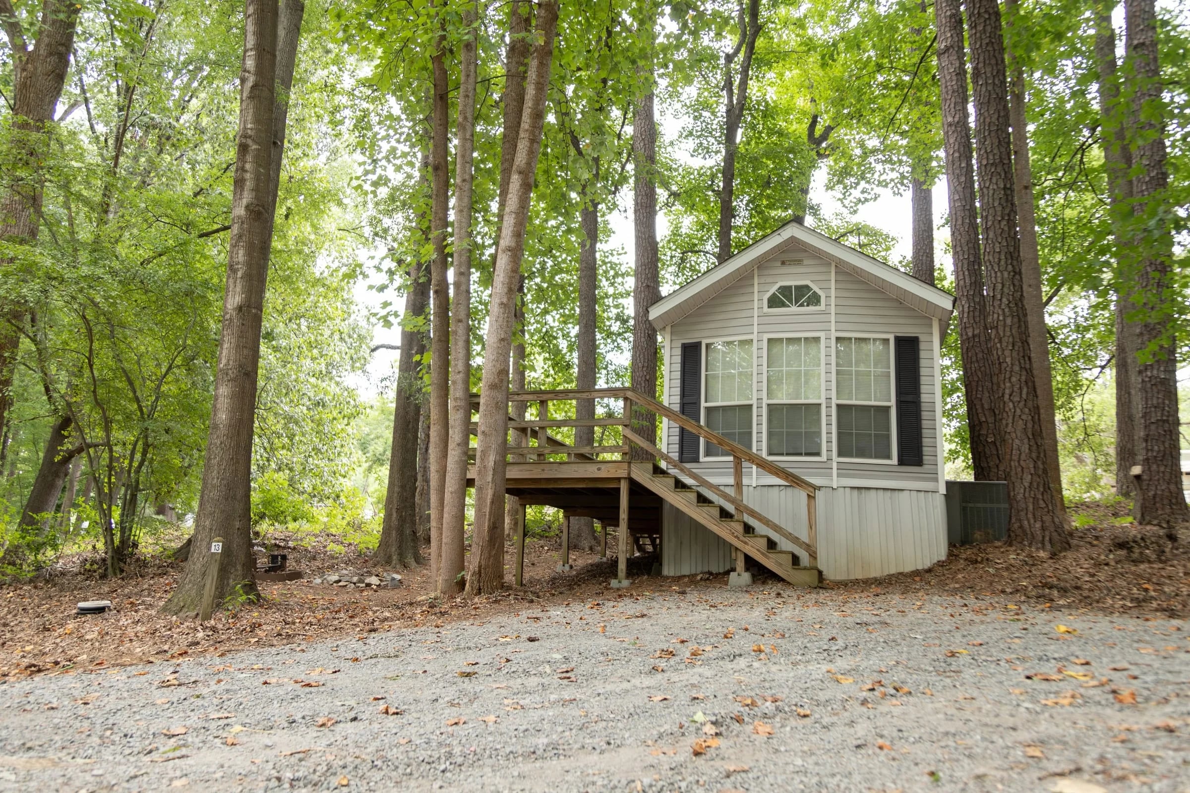 Cream park-model cottage with arched window among tall trees
