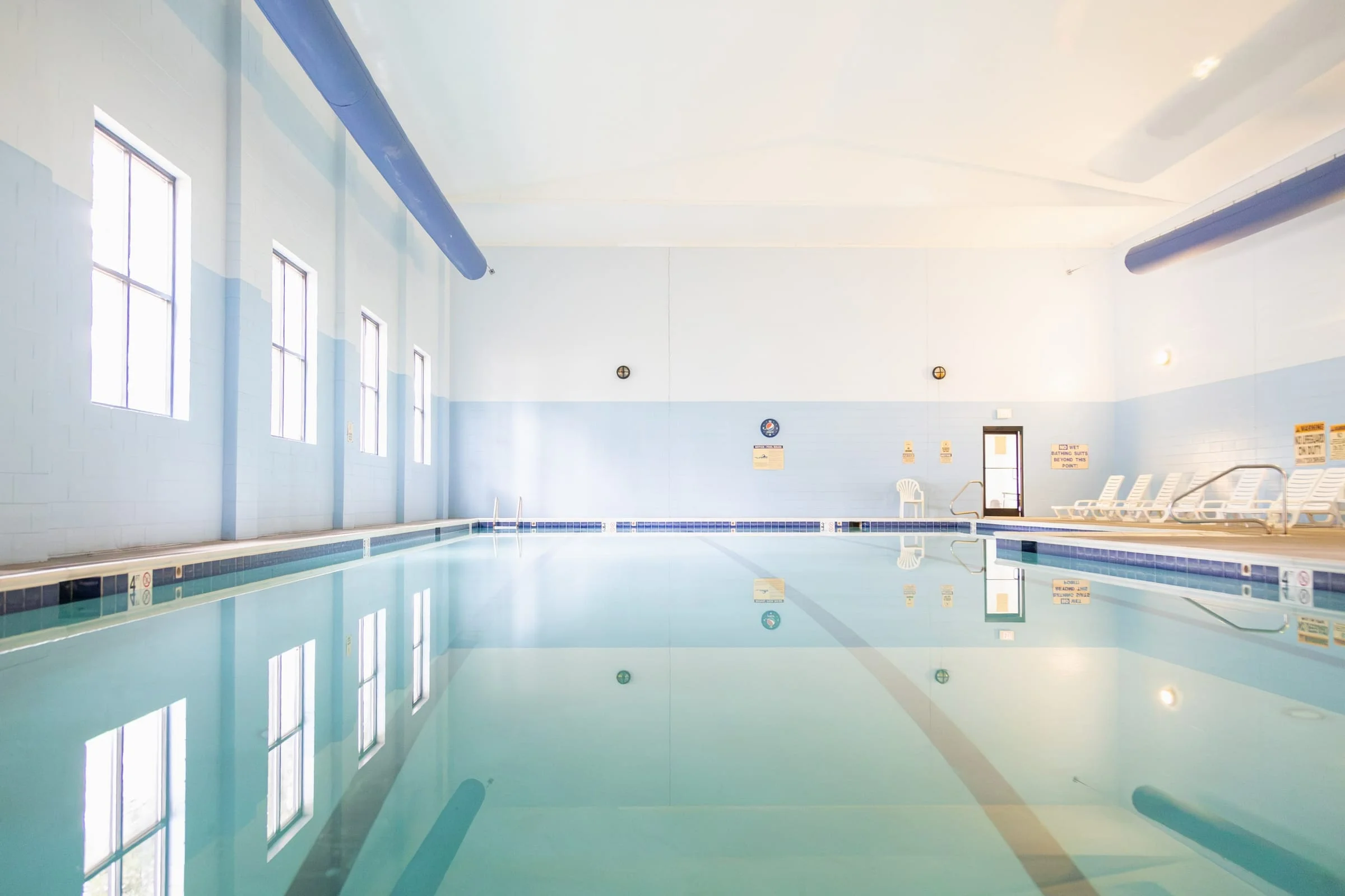 Indoor pool with loungers along the windowed wall