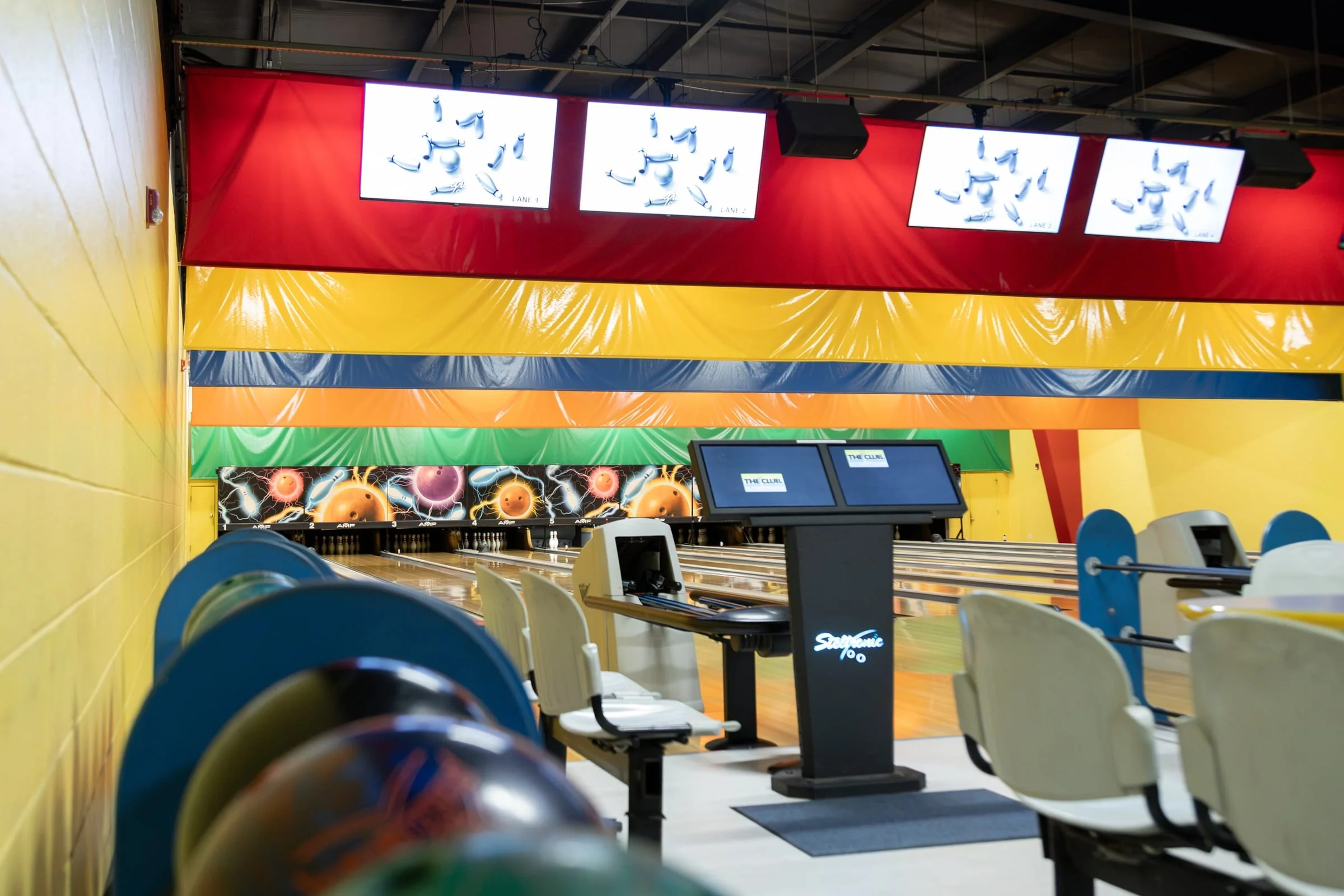Scoring consoles and TVs above the colorful bowling lanes
