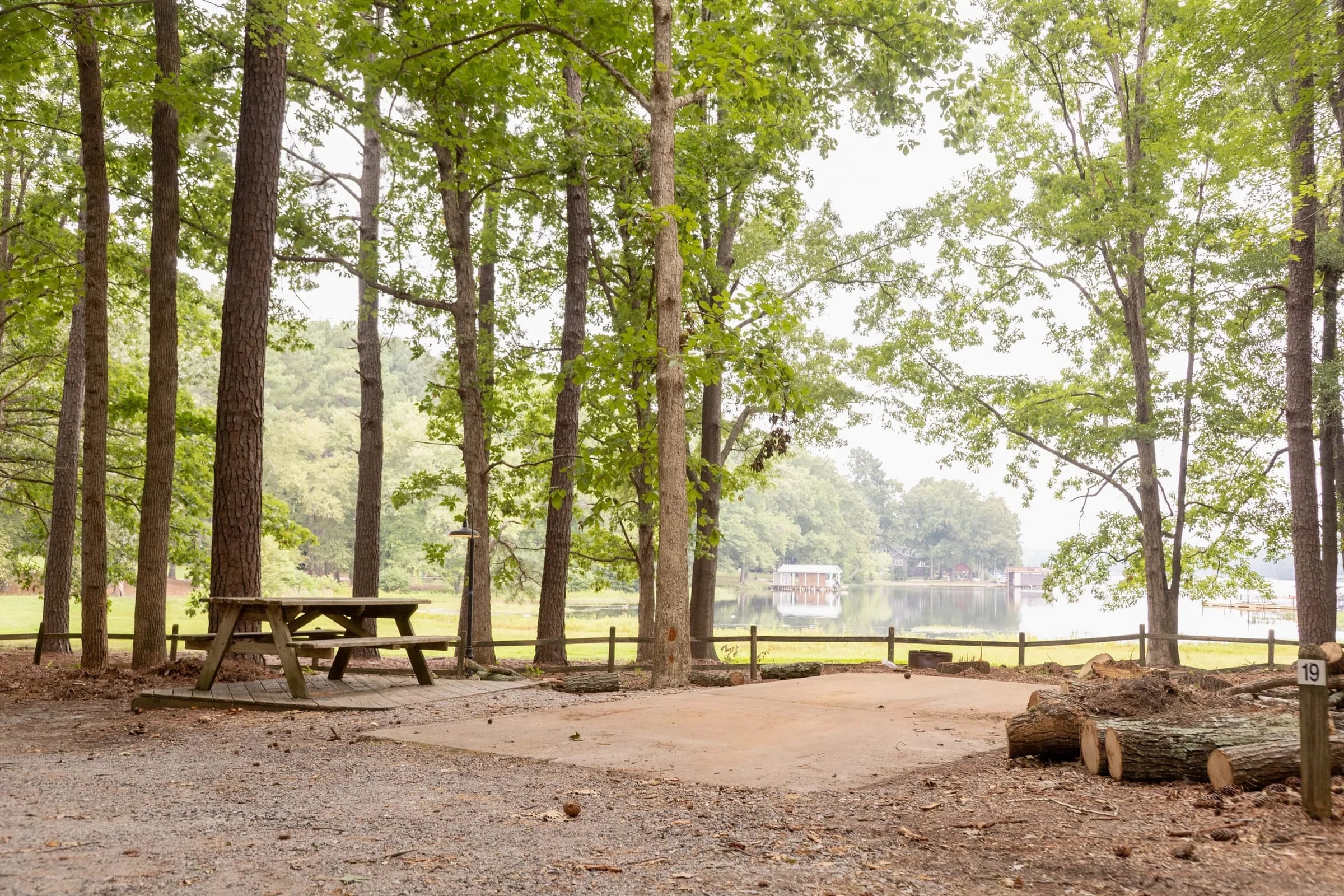 Empty wooded RV site with picnic table and a glimpse of the lake beyond