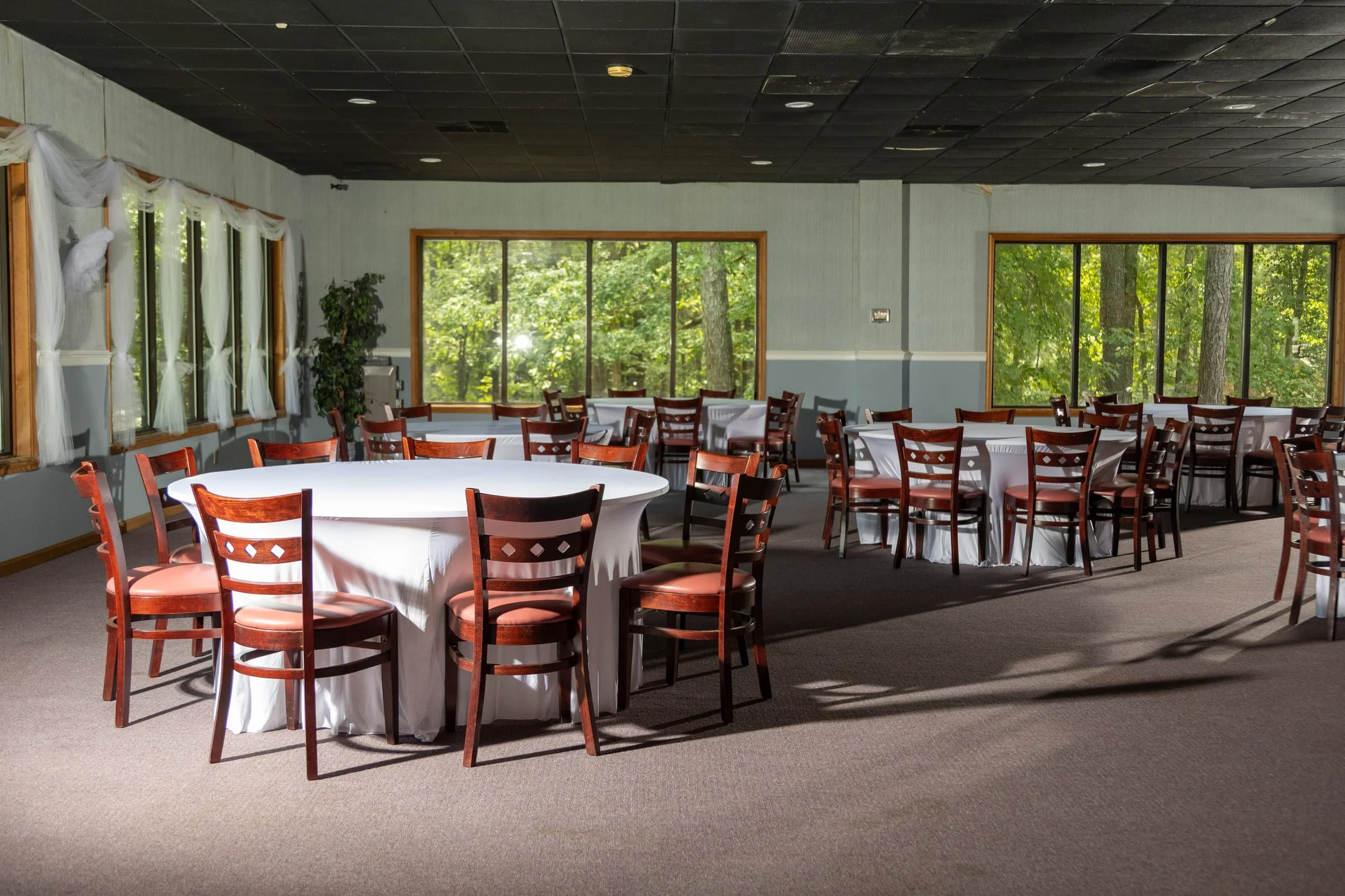 Banquet room set with clothed round tables and red chairs